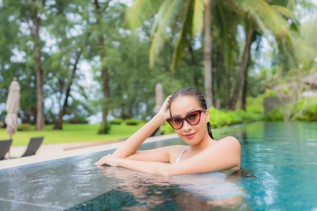 Portrait of beautiful young asian woman relaxing around outdoor swimming pool in hotel resort nearly sea