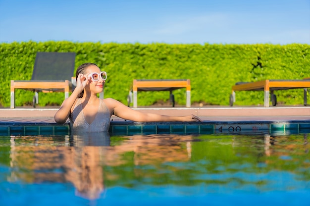 Foto gratuita ritratto di bella giovane donna asiatica che si rilassa intorno alla piscina all'aperto nella località di soggiorno dell'hotel