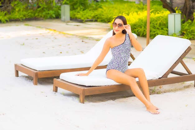 Foto gratuita ritratto bella giovane donna asiatica che si rilassa intorno alla piscina in hotel resort in vacanza