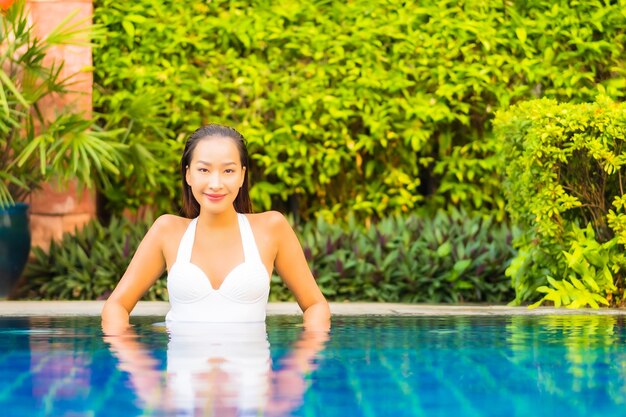 Foto gratuita ritratto bella giovane donna asiatica che si rilassa intorno alla piscina in hotel resort in vacanza