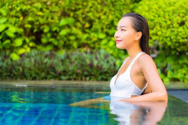 Женщина портрета красивая молодая азиатская ослабляя вокруг бассейна в курортном отеле на каникулах