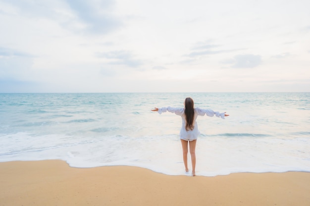 Foto gratuita ritratto di bella giovane donna asiatica che si rilassa intorno alla spiaggia all'aperto in vacanza di viaggio