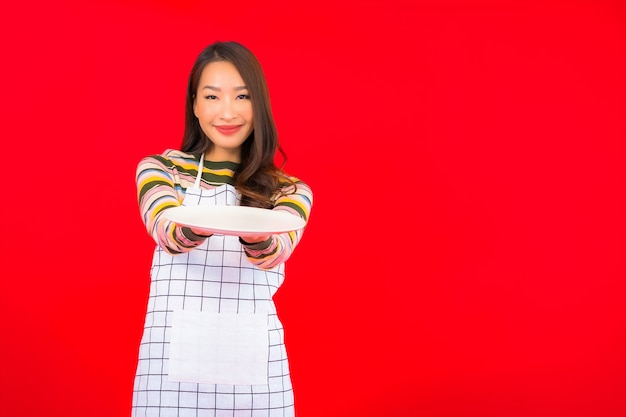 Portrait beautiful young asian woman show empty dish on red wall