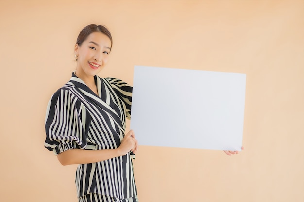 肖像画の美しい若いアジア女性は空の白い看板紙を表示します。