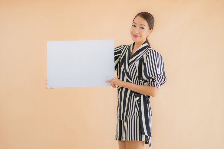 無料Photo 肖像画の美しい若いアジア女性は空の白い看板紙を表示します。