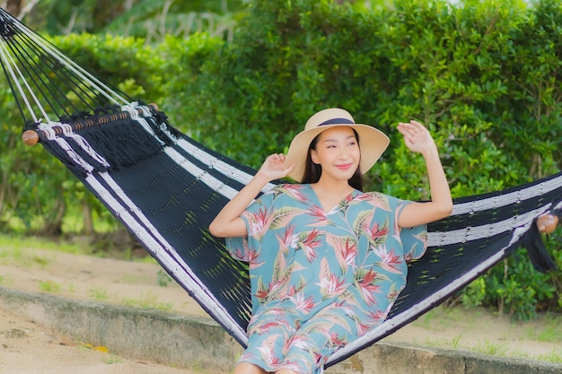 Free photo portrait beautiful young asian woman sit on hammock swing around beach sea ocean in holiday vacation