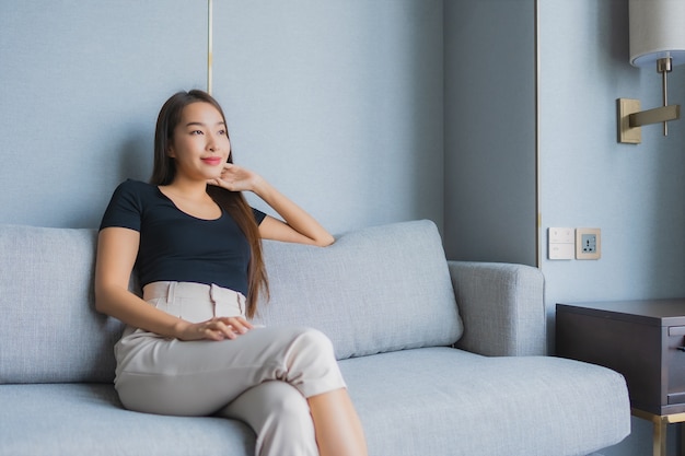소파에 앉아 초상화 아름 다운 젊은 아시아 여자는 거실에서 휴식