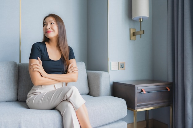 소파에 앉아 초상화 아름 다운 젊은 아시아 여자는 거실에서 휴식