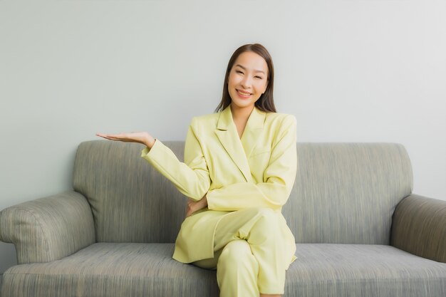 Portrait beautiful young asian woman sit with smile on sofa in living room interior