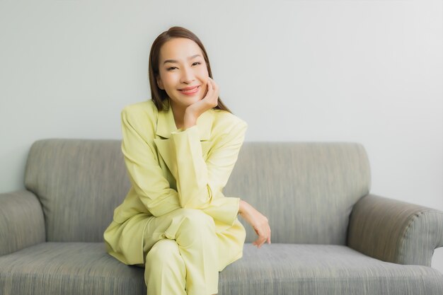 Portrait beautiful young asian woman sit with smile on sofa in living room interior