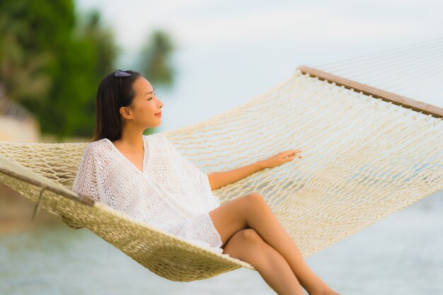 海のビーチの周りのハンモックの上に座っての肖像画美しい若いアジア女性リラックス