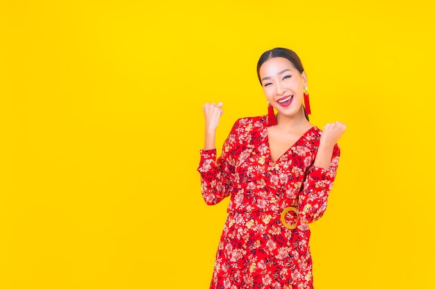 Portrait beautiful young asian woman smile in action in chinese new year concept on color wall