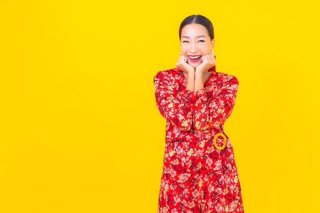 Portrait beautiful young asian woman smile in action in chinese new year concept on color wall