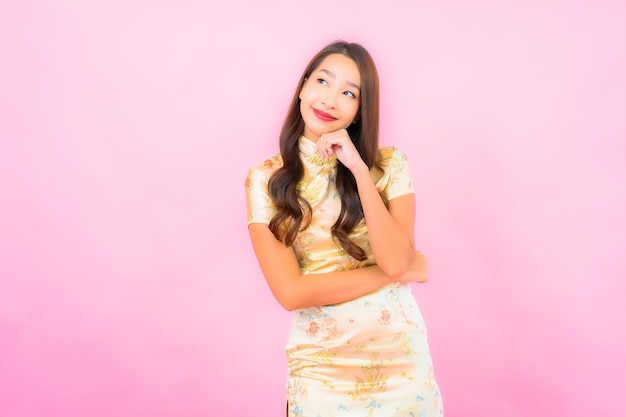 Portrait beautiful young asian woman smile in action with chinese new year concept on pink color wall