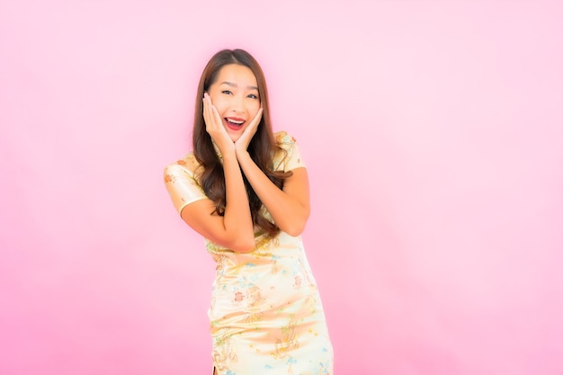 Portrait beautiful young asian woman smile in action with chinese new year concept on pink color wall