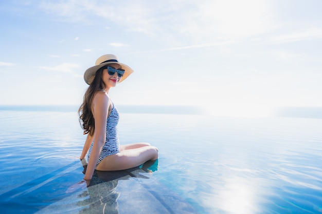 Free photo portrait beautiful young asian woman smile happy relax around swimming pool in hotel resort for leisure