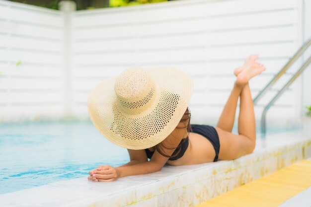 Portrait beautiful young asian woman smile happy relax around swimming pool in hotel resort for leisure