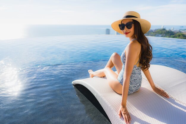 Portrait beautiful young asian woman smile happy relax around swimming pool in hotel resort for leisure