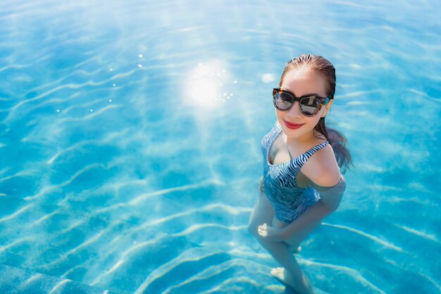 Portrait beautiful young asian woman smile happy relax around swimming pool in hotel resort for leisure