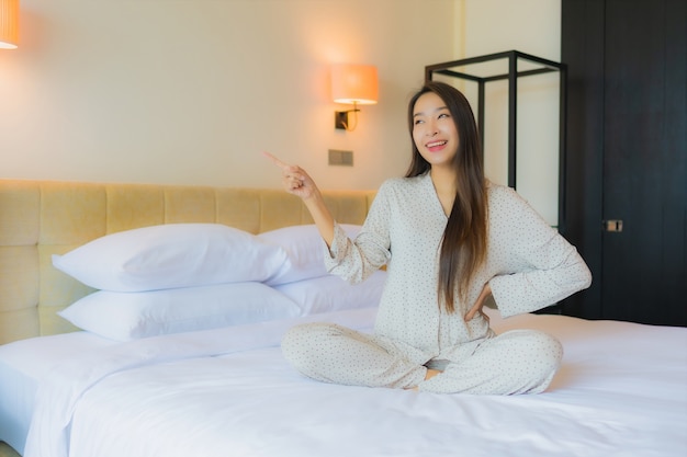 Улыбка красивой молодой азиатской женщины портрета счастливая ослабляет на кровати