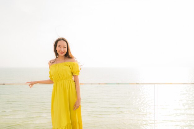 Улыбка женщины портрета красивая молодая азиатская счастливая и ослабляет на внешнем балконе с пляжем моря и oce