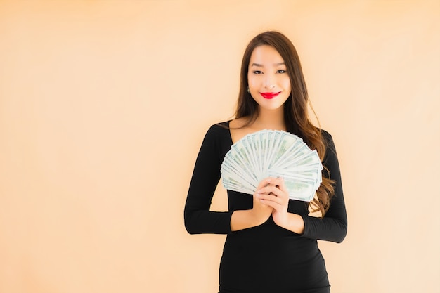 肖像画の美しい若いアジア女性はお金と現金で幸せな笑顔