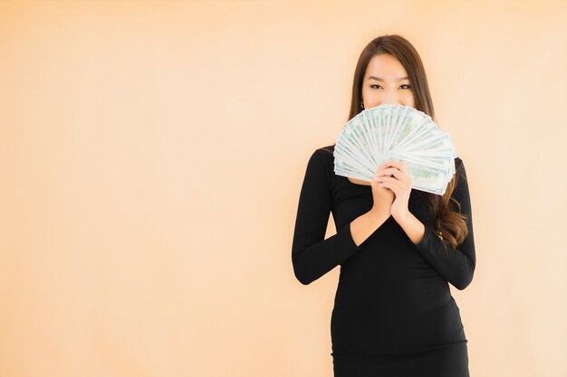 肖像画の美しい若いアジア女性はお金と現金で幸せな笑顔