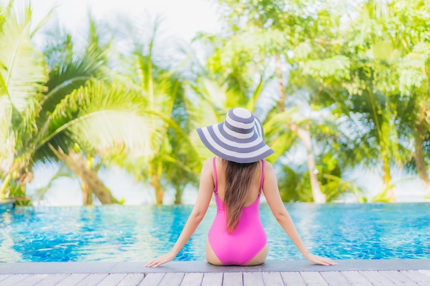 Улыбка женщины портрета красивая молодая азиатская ослабляет вокруг открытого бассейна в курортном отеле на отключении перемещения каникул праздника