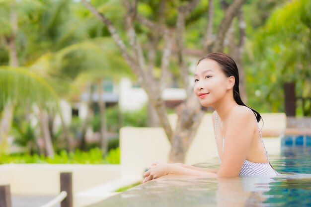 肖像画美しい若いアジアの女性の笑顔は、休日の休暇旅行旅行でリゾートホテルの屋外スイミングプールの周りでリラックス