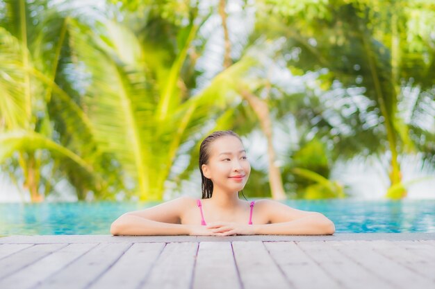 초상화 아름 다운 젊은 아시아 여자 미소 휴가 휴가 여행 여행에 리조트 호텔의 야외 수영장 주변에서 휴식