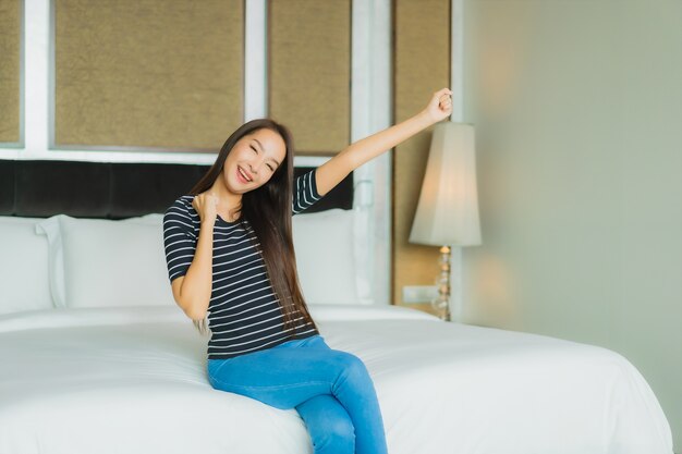 Portrait beautiful young asian woman smile relax on bed in bedroom interior