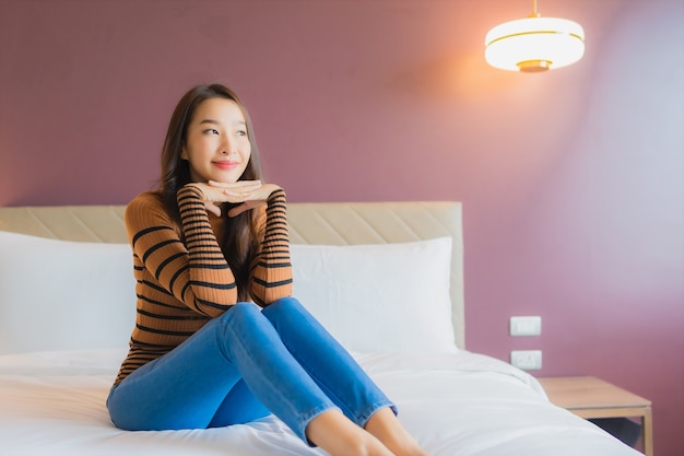 Улыбка женщины портрета красивая молодая азиатская ослабляет на кровати