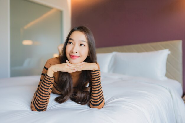 Free photo portrait beautiful young asian woman smile relax on bed