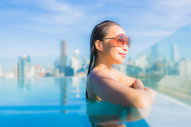 세로 아름 다운 젊은 아시아 여자 미소 도시 전망 야외 수영장 주변 레저 휴식