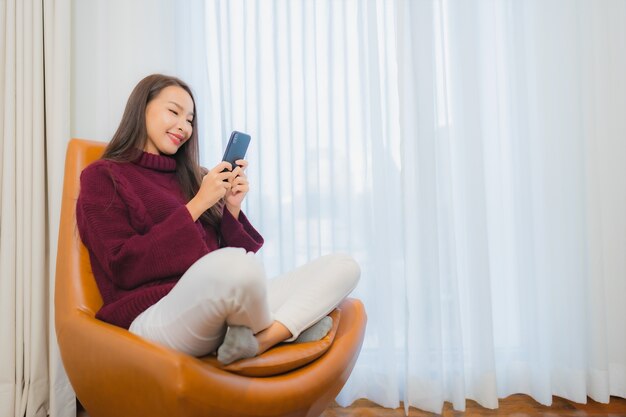 세로 아름 다운 젊은 아시아 여자 미소 거실 인테리어에 소파에 휴식