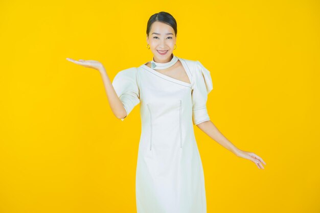 Улыбка женщины портрета красивая молодая азиатская с действием на цветном фоне