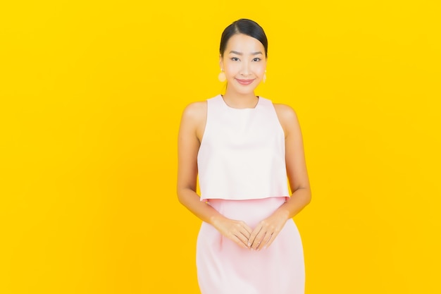 무료 사진 노란색에 행동과 초상화 아름 다운 젊은 아시아 여자 미소