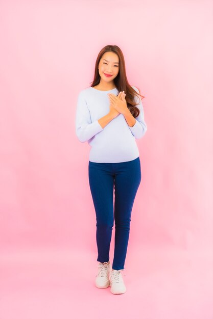 Portrait beautiful young asian woman smile with action on pink isolated wall