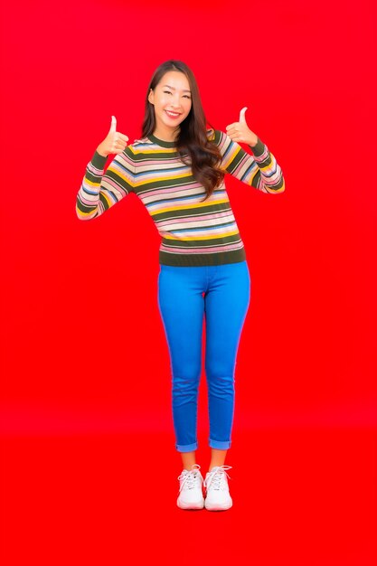 Portrait beautiful young asian woman smile with action on red isolated wall