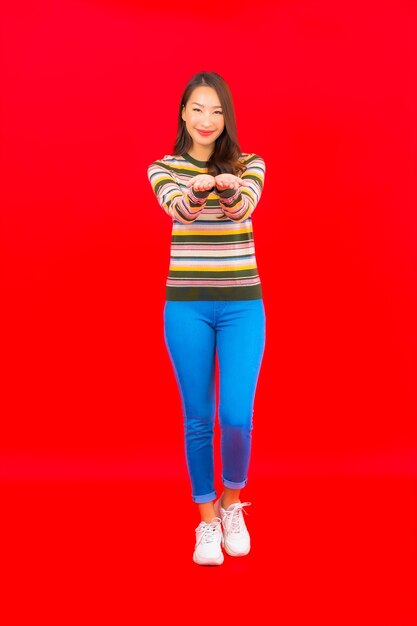 Portrait beautiful young asian woman smile with action on red isolated wall