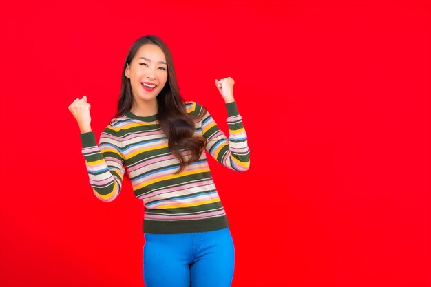 Portrait beautiful young asian woman smile with action on red isolated wall