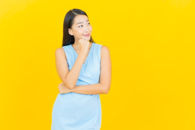 Portrait beautiful young asian woman smile with action on yellow color wall