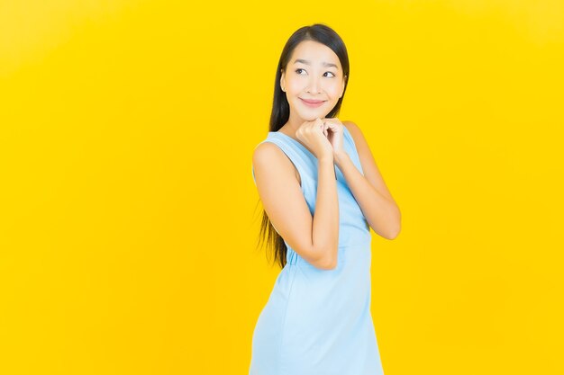 노란색 벽에 행동과 초상화 아름 다운 젊은 아시아 여자 미소