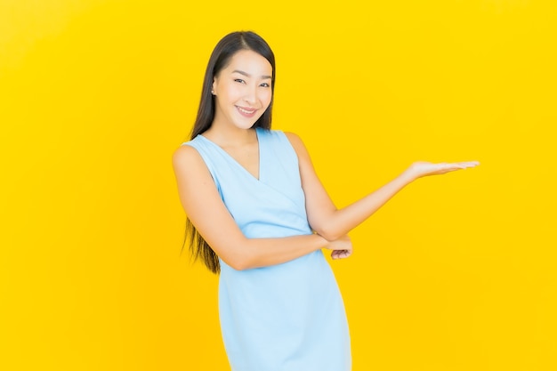 Portrait beautiful young asian woman smile with action on yellow color wall