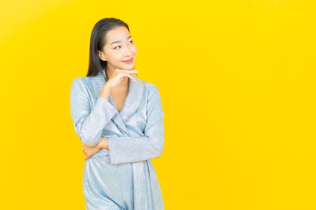 노란색 벽에 행동과 초상화 아름 다운 젊은 아시아 여자 미소