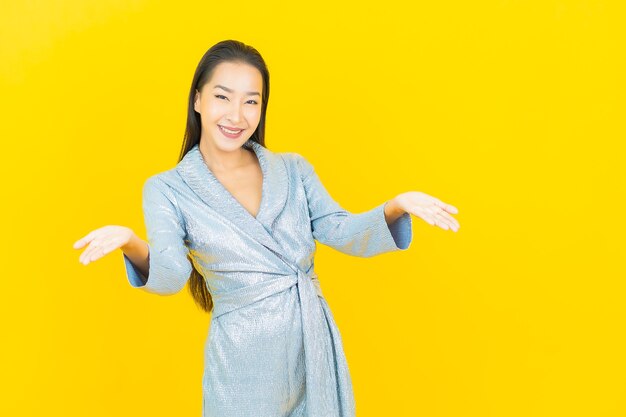 노란색 벽에 행동과 초상화 아름 다운 젊은 아시아 여자 미소