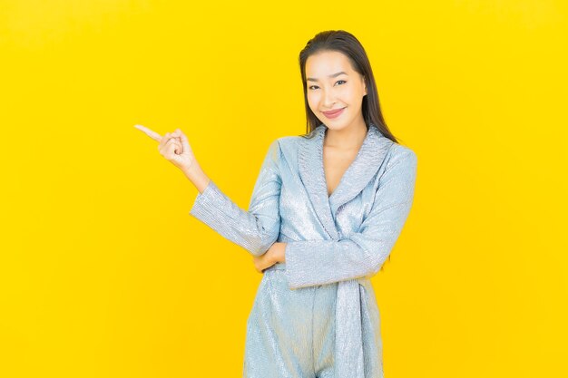 Portrait beautiful young asian woman smile with action on yellow wall