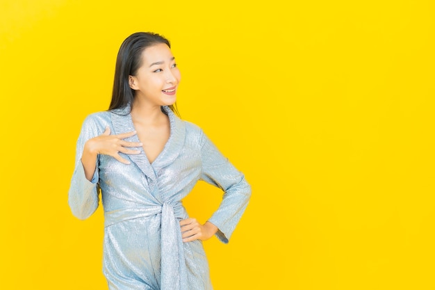 黄色の壁にアクションと肖像画美しい若いアジアの女性の笑顔