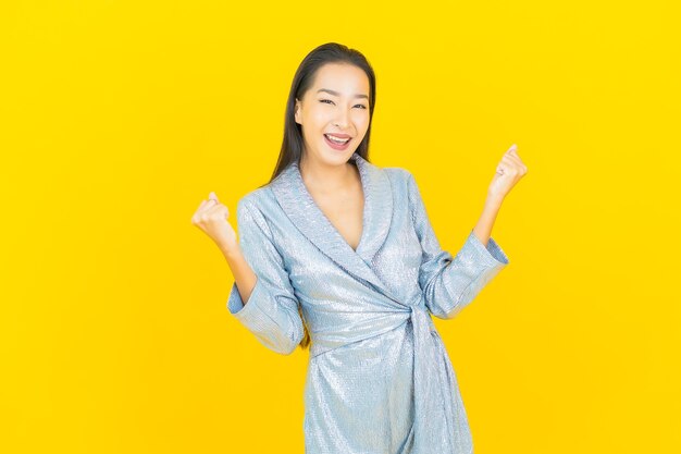 Portrait beautiful young asian woman smile with action on yellow wall