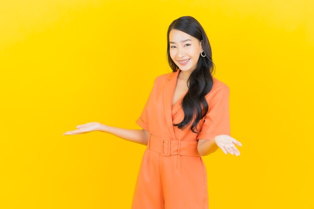 Portrait beautiful young asian woman smile with action on yellow